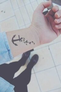 Kleines Anker Tattoo Motiv mit Vögeln am Unterarm