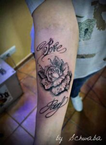 Realistische Rose Tattoo Idee mit Schriftzug am Unterarm