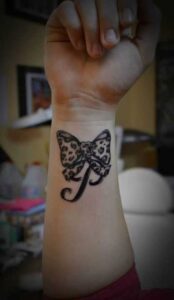 Leoparden-Schleife mit Initial Tattoo Idee am Unterarm