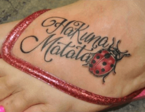 Hakuna Matata Schriftzug Tattoo mit Marienkäfer am Fuß