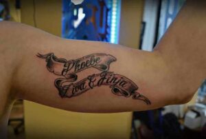 Namen Tattoo Idee auf Banderole mit Schatteneffekt am Oberarm