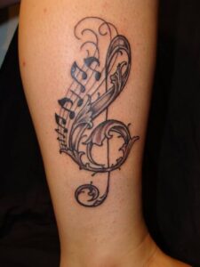 Notenschlüssel Tattoo Motiv mit Ornamenten am Bein