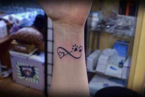 Unendlichkeitszeichen Tattoo Idee mit Herz und Pfoten am Unterarm